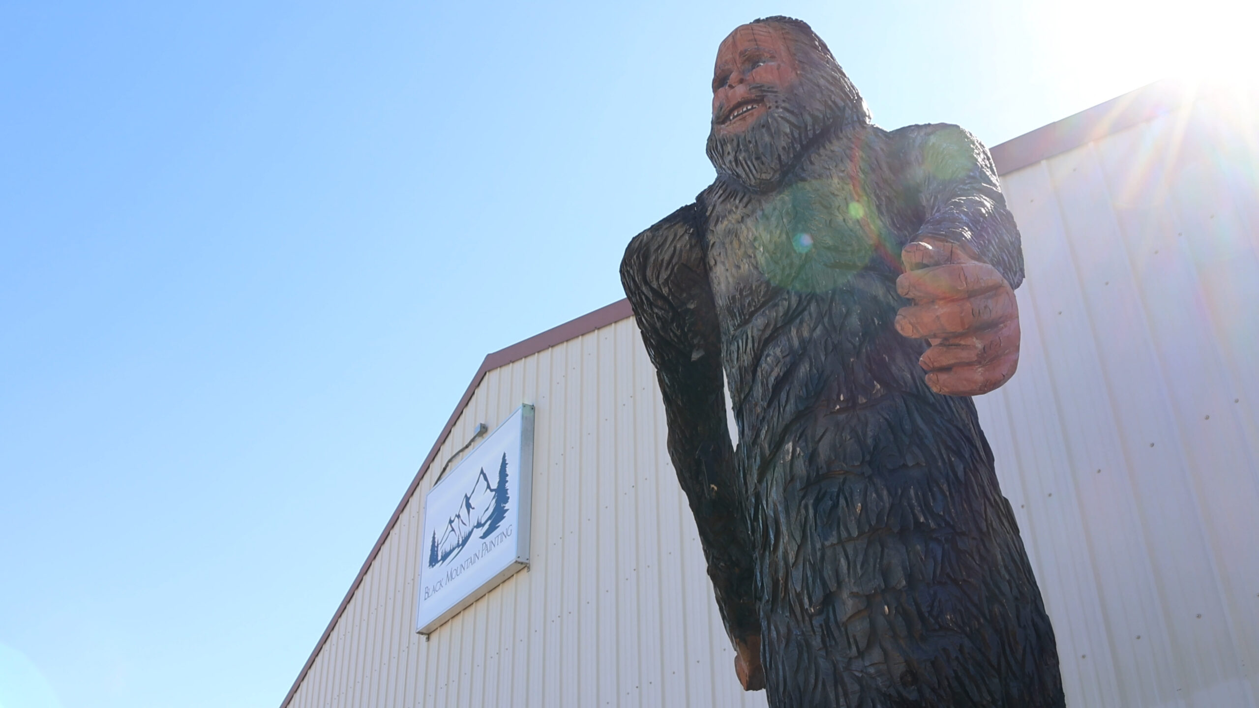 Front sign of Black Mountain Painting Building on E. Colorado Boulevard in Spearfish alongside front of sasquatch.