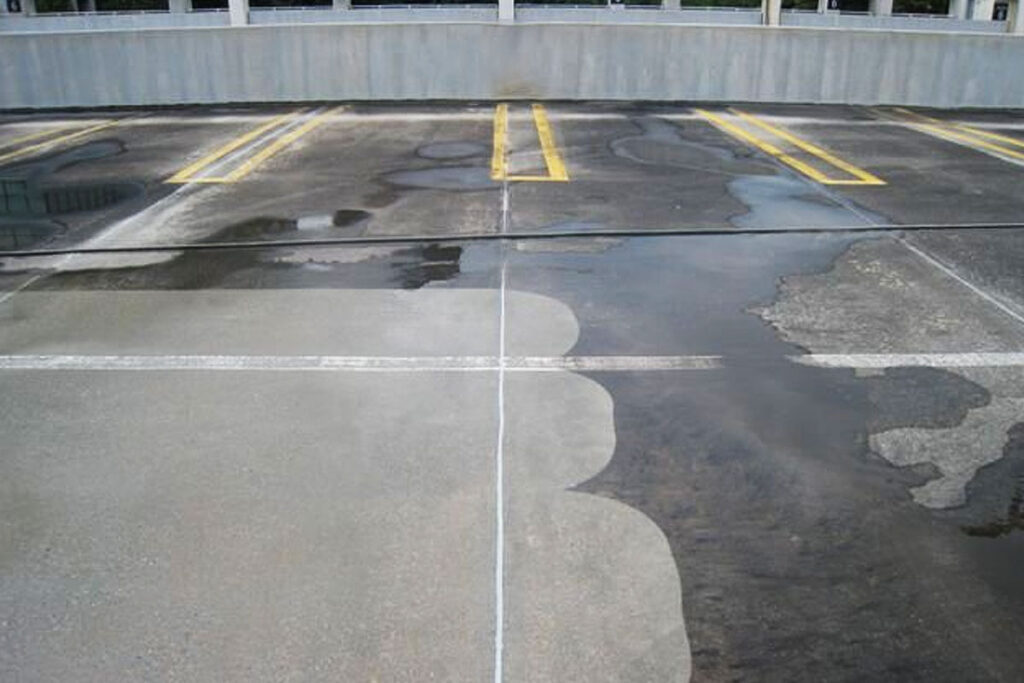 Parking lot with dry and wet spots after pressure washing services.