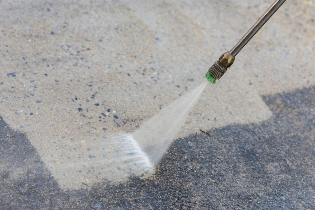 Pressure washing expert using pressure washer to remove dirt and grime from driveway.